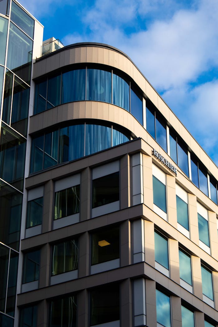 Low angle view of a modern glass facade office building against a blue sky.