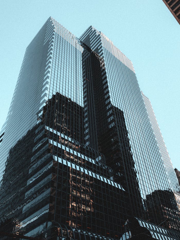 Dramatic view of a modern glass skyscraper reflecting the clear blue sky.