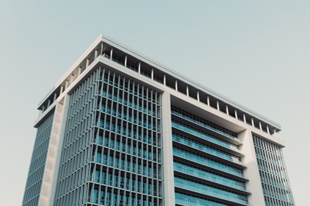 Architectural shot of a modern high-rise office building with a prominent glass facade, shot at daytime.