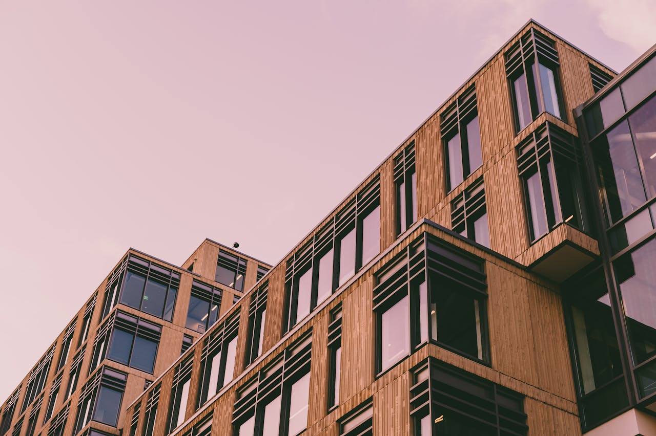 From below of modern geometric building with windows and balconies located against cloudless sky