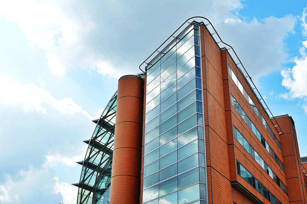 A tall, modern building with glass windows reflecting the sky, showcasing urban architecture.